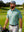 Model in beryl green everyday classic solid polo holding a golf club outdoors, waist-up shot