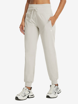 Model wearing women's stretch fleece lined water resistant joggers in oyster gray, showcasing the front lower body view.