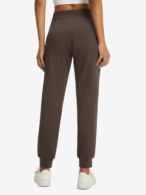 Model wearing women's stretch fleece lined water resistant joggers in coffee brown, showing the back lower body view.