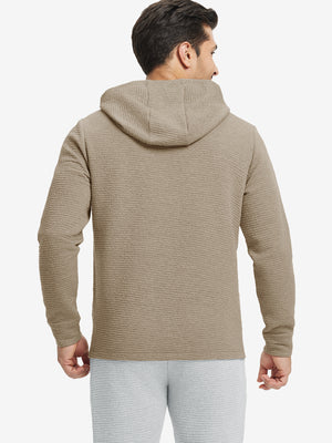 Back view of model wearing texture solid hoodies pullover showing fit and hood detail, light brown heather.