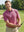 Model in rose flower performance jersey print polo holding a golf club outdoors, half-body shot