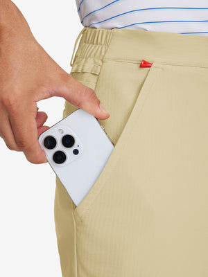 Hand placing an iPhone into pocket of lightweight flat front casual trousers in khaki.