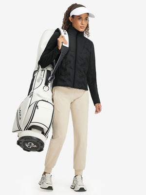 Model carrying a golf bag, wearing women's lightweight fleece-lined puffer jacket in black.
