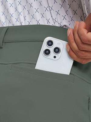 Close detail of hand placing phone into back pocket of lightweight moisture wicking dress pants in slate green.