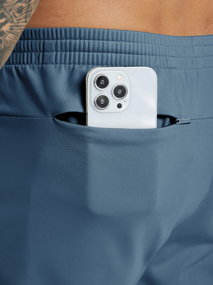 Back pocket detail of Water Resistant Comfy Fleece Golf Joggers in bluish grey, holding smartphone