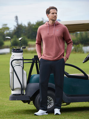 Model in brick heather classic heather fleece hoodies standing in front of a golf cart on the course