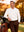 Front upper body angled shot of model wearing white solid stretch cotton pique long sleeve polo shirt with hand on golf bag on the golf course