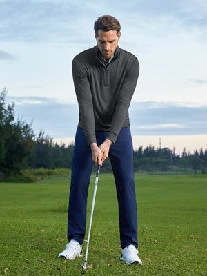Model preparing to swing on course, wearing quarter zip melange pullover in dark grey heather with sporty look