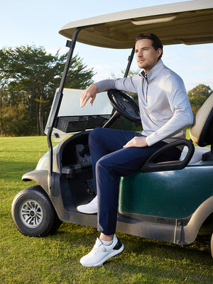Model in grey melange pinstripe quarter zip pullover sitting on a golf cart, full-body shot