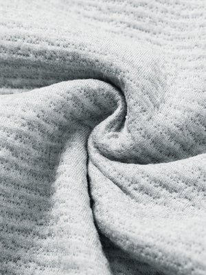 Close-up fabric detail of soft sweatpants with 4 zipper pockets, smooth texture and cozy light grey heather feel