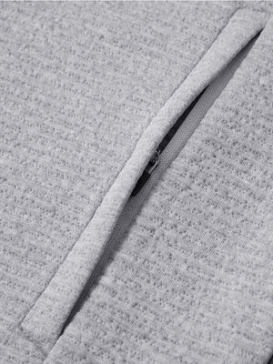 Close-up of jacket pocket showing fine stitching and insulation detail, textured insulated winter jacket, light grey heather.