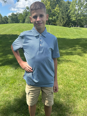 Youth model in aqua stripe performance cooling polo standing outdoors with hands on hips, full-body shot